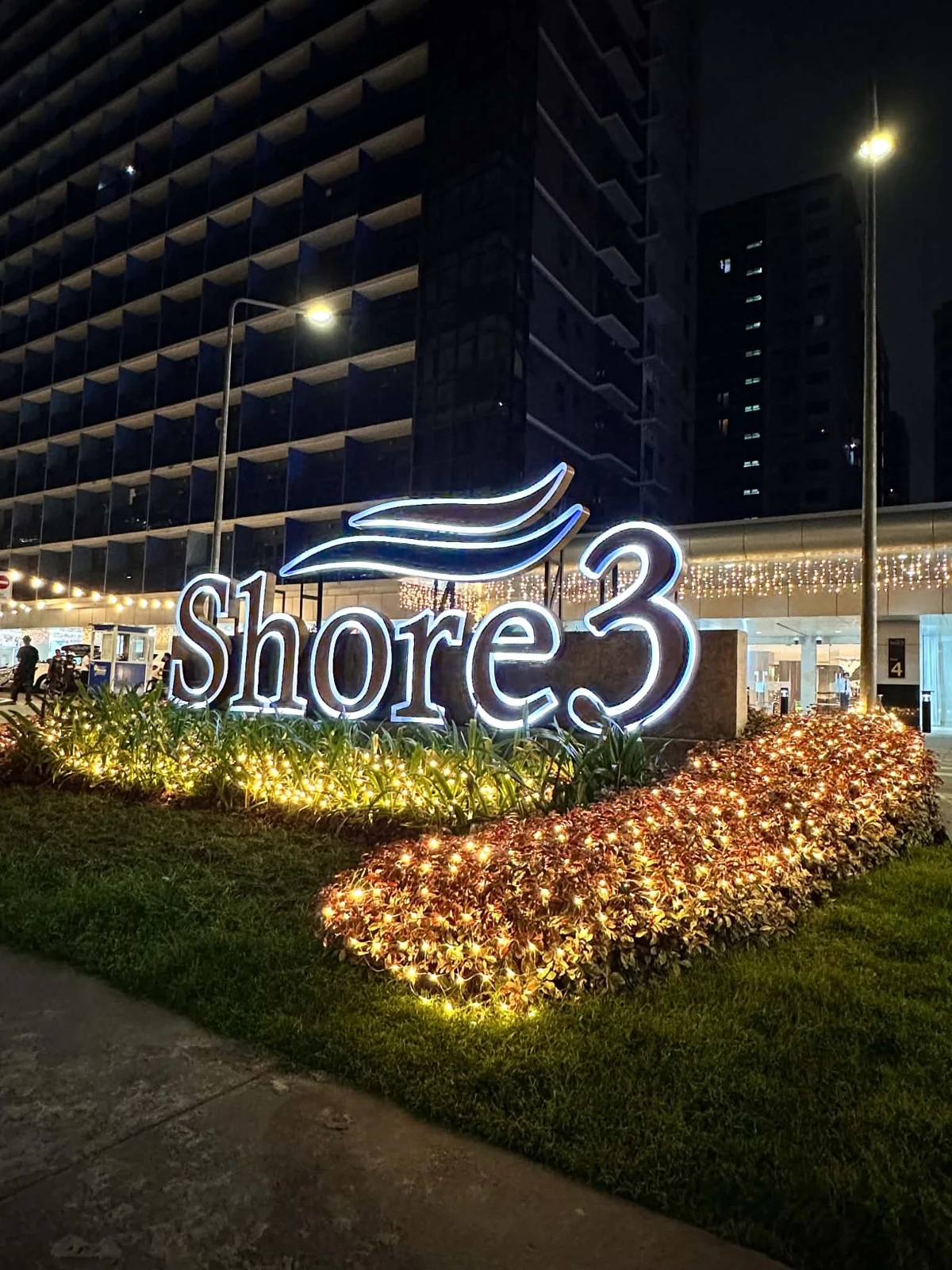 Illuminated Shore 3 sign and buildings at night